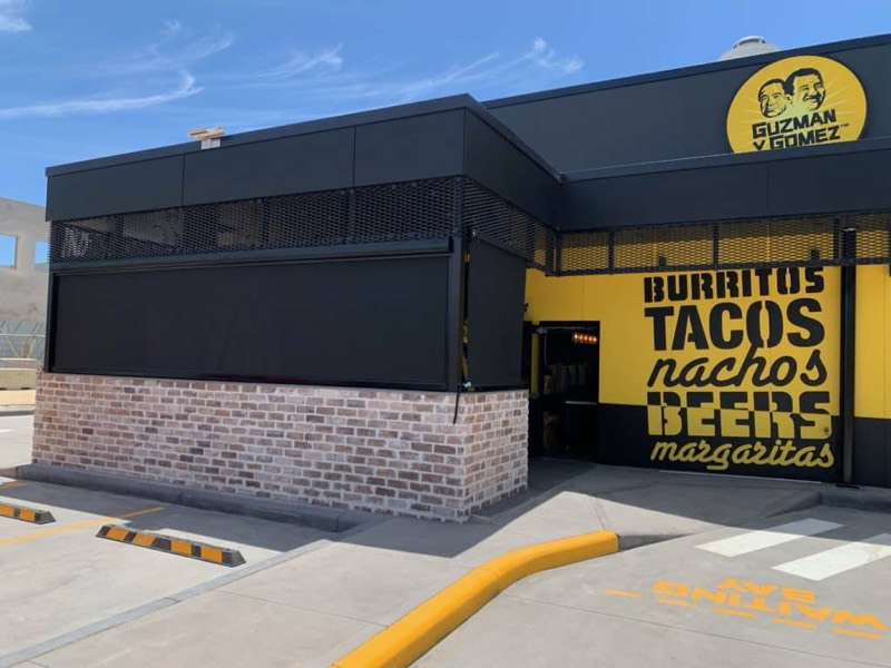 Fast food outlet with bold yellow signage and outdoor blinds along the frontage