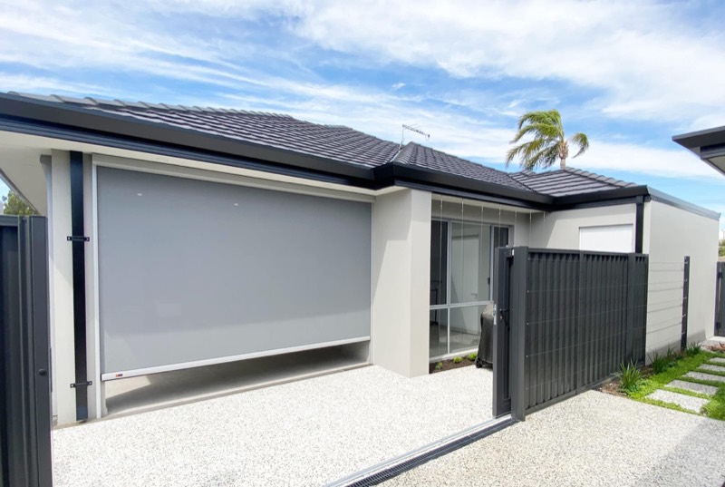 Modern home with an outdoor blind lowered on the side elevation beside a driveway