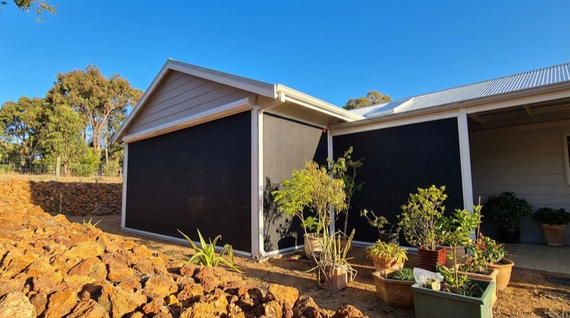 Outdoor blinds lowered on a home with newly landscaped garden beds