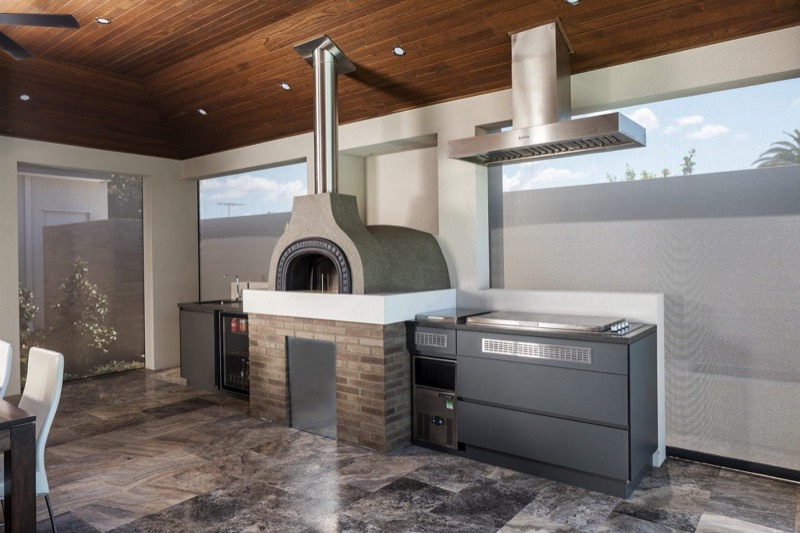Built-in barbecue and pizza oven along a stone bench under a covered alfresco